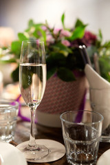 a glass of wine with bubbles on the background of flowers at the banquet table in a restaurant