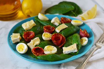 Salad with spinach, brie cheese and quail eggs.