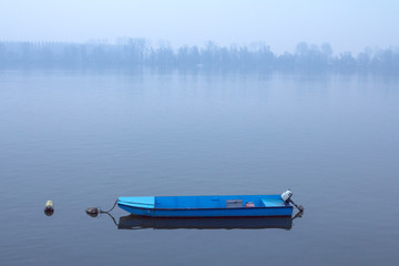 Rowing boat on the Danube on a foggy dusk in winter in Zemun, Belgrade, Serbia..Picture of a small wooden boat on a misty sunset on the Danube in Zemun, suburb of Belgrade © Jerome