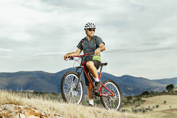 Fototapeta na wymiar Adult man on mountain bike in a mountain landscape. Looking a landscape