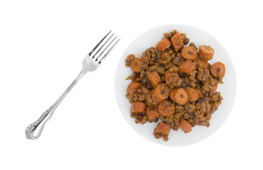 Beans and hot dogs on a plate with a fork to the side isolated on a white background.