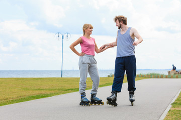 Young couple holding hands while rollerblading