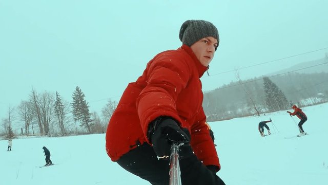 snowboarder taking selfie while climbing mountain. snowboarder rides on the board in the snow and relieves himself