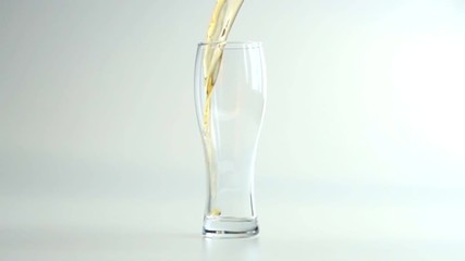 Pouring beer into the glass in slow motion on white background