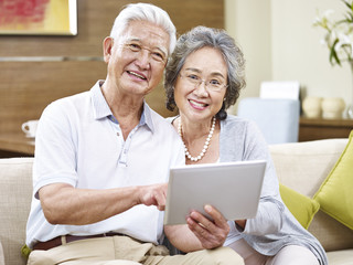 happy asian senior couple using tablet at home