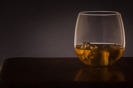 glass of whiskey backlit on a dark background