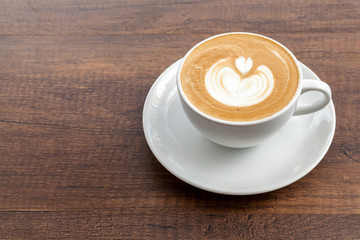Coffee cup of latte art on wooden background with copy space