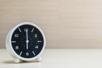 Closeup alarm clock for decorate in 6 o'clock on brown wood desk and wall textured background with copy space