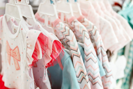 Girl's dresses on hangers on a rack in a department store.