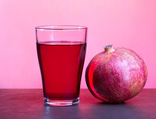 A glass of pomegranate juice with pomegranate fruits on wooden table. Healthy drink concept.