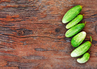 Juicy ripe green cucumbers on old wooden background. Closeup.