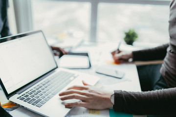 Men sitting at a table using a laptop and taking notes.