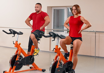 young couple bycicle cycling in gym