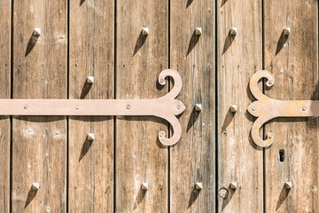 Detail of an old wooden door with metal hinge