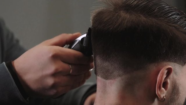 Handsome man doing a close up haircut for man with black hair at barber shop, modern hair stylist, close up.
