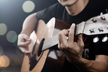 Man playing acoustic guitar with finger catching chord on bar on