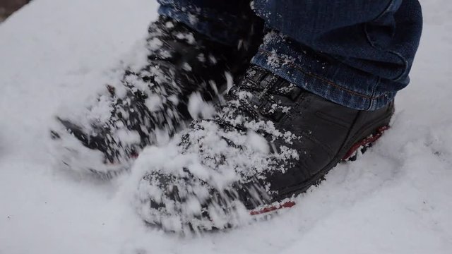 Man shaking the snow off his feet, shoes