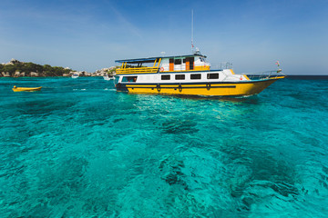 Fototapeta na wymiar Tourist boat near island shore with turquoise clear transparent water