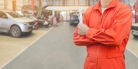 Mechanic holding wrench in car garage, Mechanic and tools concept.