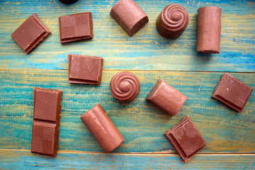 pieces of chocolate and chocolate candies on a blue wooden background