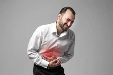Man suffering from abdominal pain on gray background. Health care concept