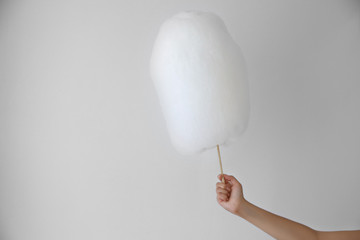 Female hand holding cotton candy on light background