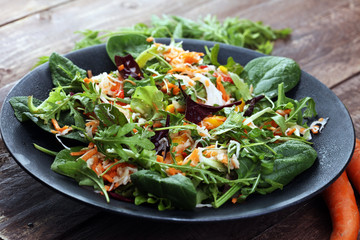 Fresh diet fitness salad of daikon radish, carrots, flax seeds, arugula. Vegan cuisine.