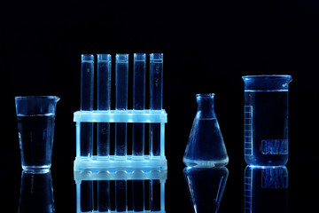 Chemical flasks and test-tubes on black background