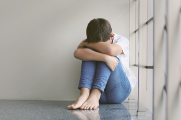 Sad little boy sitting beside wall