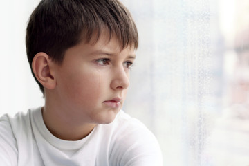 Sad little boy on blurred background, closeup