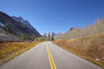 Scenic mountain road, Maroon Bells in distance, travel concept, USA.