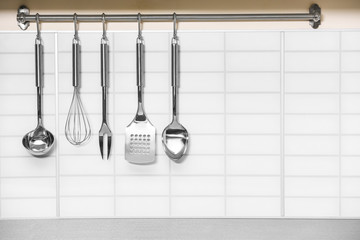 Set of metal kitchen utensils hanging on wall