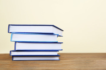 Pile of books on wooden table and beige background