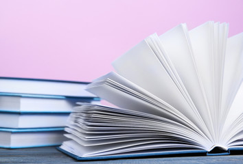 Books on wooden table and pink background