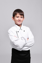 Cute boy in chef uniform on light background