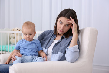 Depressed young woman with cute baby at home