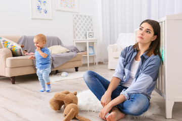 Depressed young woman with cute baby at home