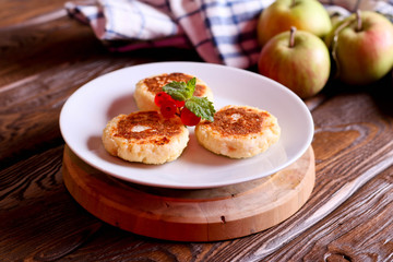 Cheese pancakes, syrniki with red currant on a white plate