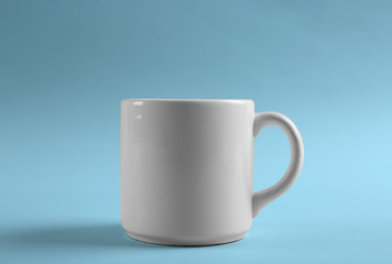 Blank ceramic cup on color background