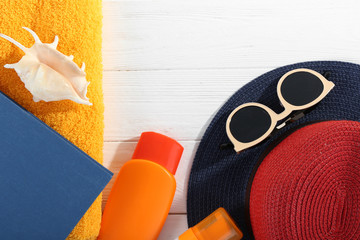 Vacation concept. Book and sunscreen things on white wooden table