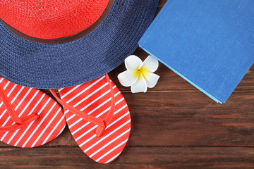 Vacation concept. Book, hat and flip-flops on wooden table