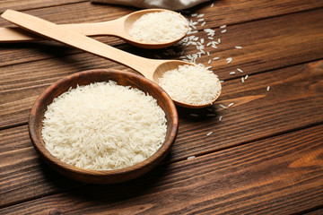 Spoons and bowl with rice on wooden table