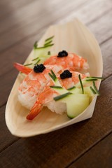 Three nigiri sushi served in wooden boat plate