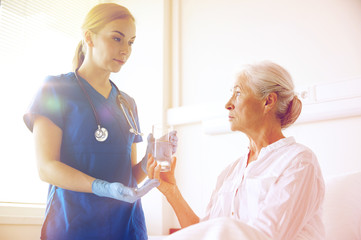 nurse giving medicine to senior woman at hospital