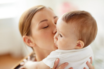 happy young mother kissing little baby at home