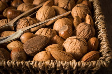 delicious assortment of nuts in a woven basket on wooden backgro