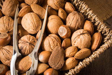 delicious assortment of nuts in a woven basket on wooden backgro
