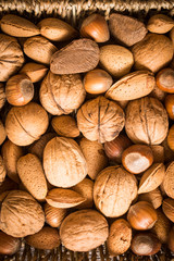 delicious assortment of nuts in a woven basket on wooden backgro