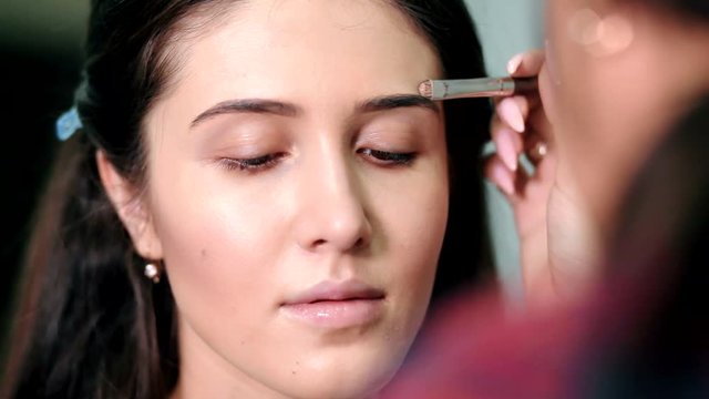 Makeup artist doing perfect make up of young girl