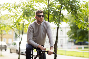Fototapeta premium young man in shades riding bicycle on city street